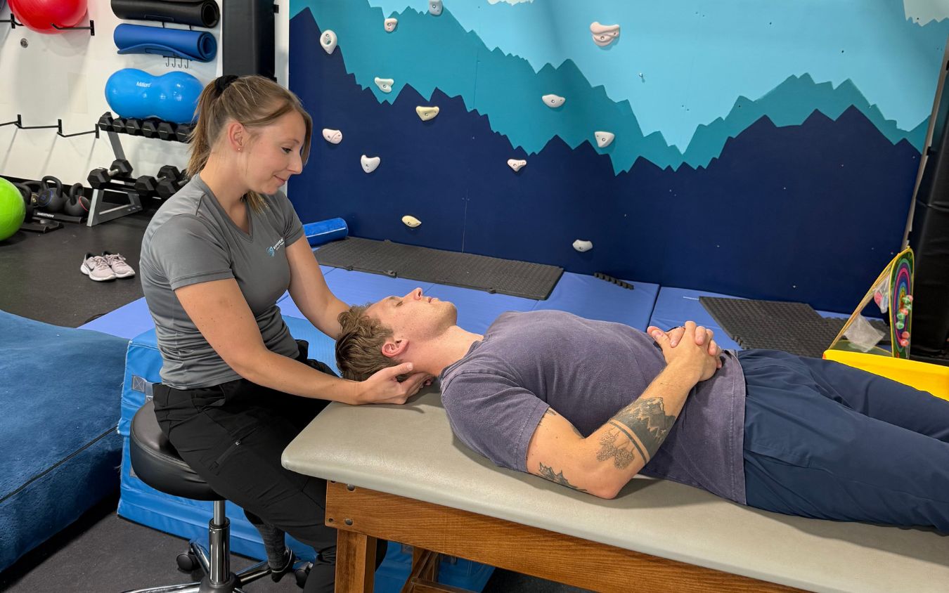 A physical therapist works with an adult client on a treatment table